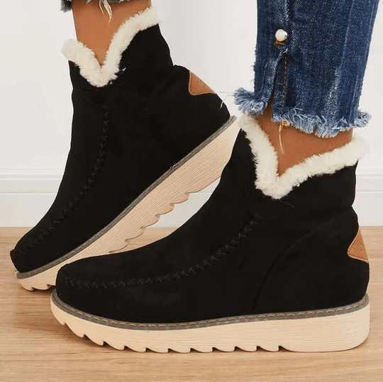 Black suede winter ankle boots with fluffy fleece trim and a cream rubber sole, worn with cuffed jeans
