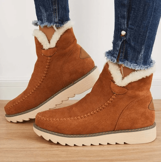 Brown suede winter ankle boots with fluffy fleece trim and a cream rubber sole, worn with cuffed jeans