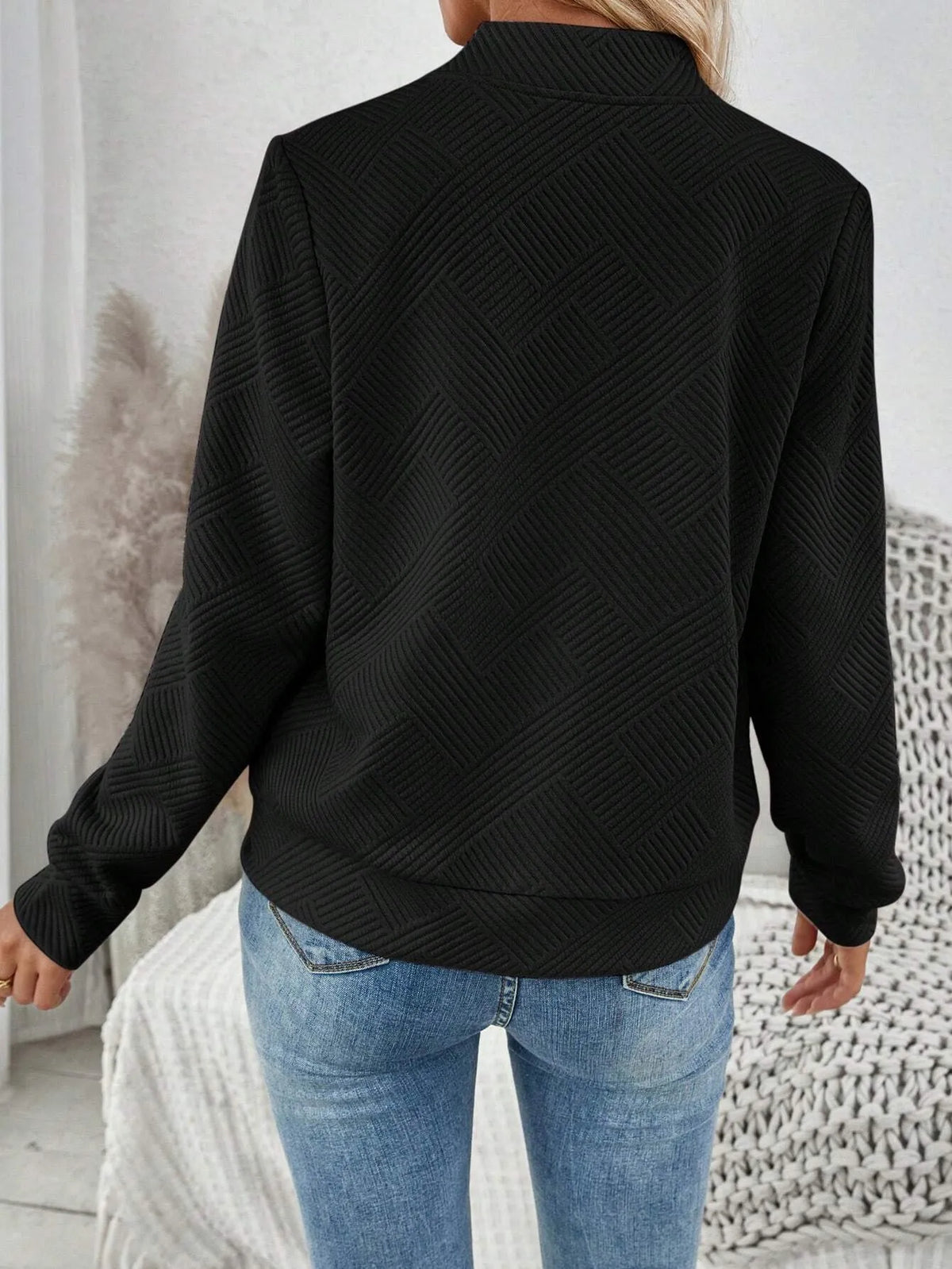 Back view of the black textured bomber jacket with blue jeans