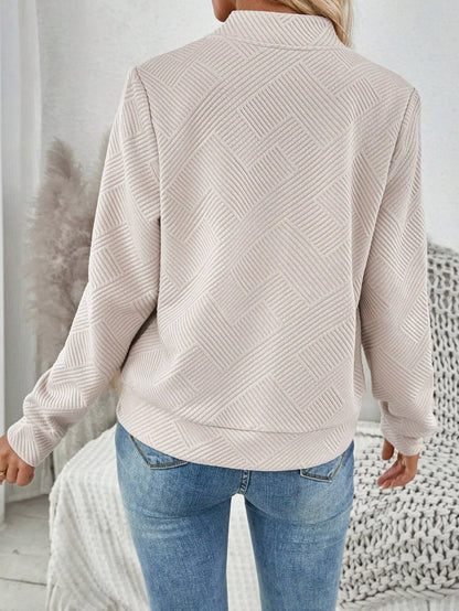 Back view of the beige textured bomber jacket with a ribbed hem and blue jeans