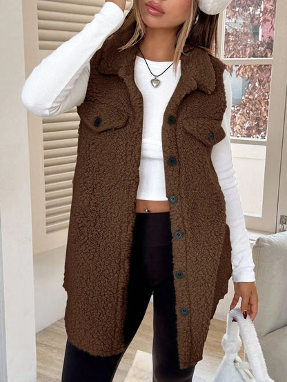 Front view of the brown teddy fleece long vest with chest pockets over a white top and black pants