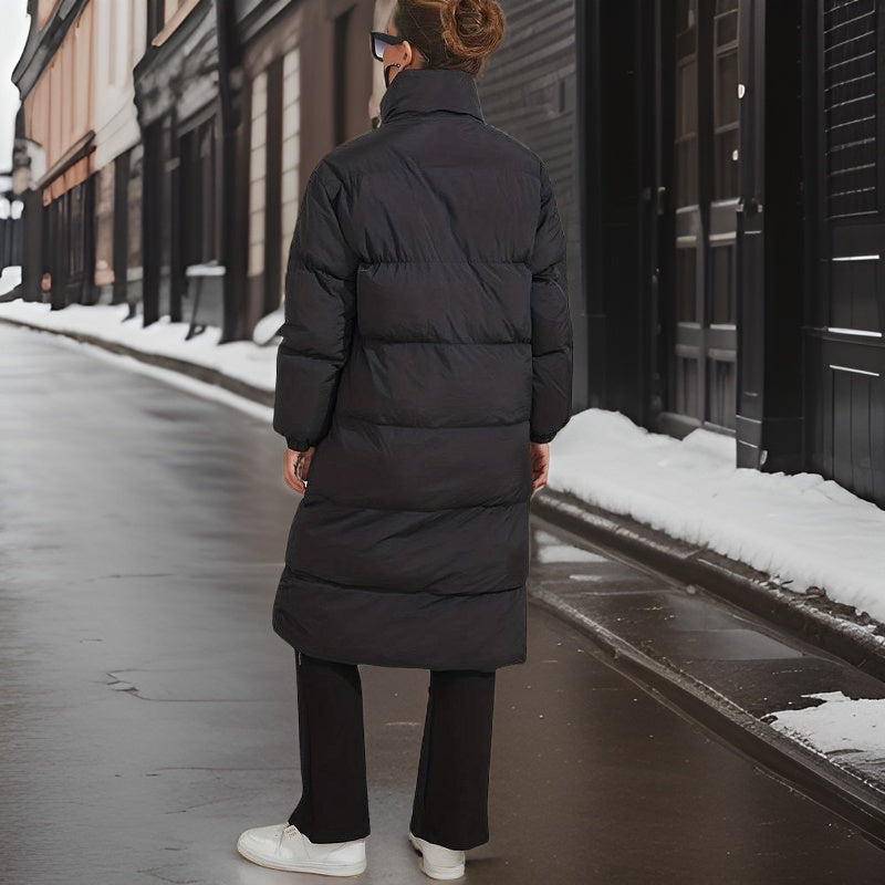 Back view of the long black quilted puffer jacket with a high collar on a wet street