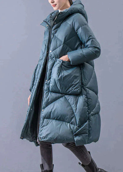 Woman wearing a long teal quilted hooded winter coat with front pockets, front view