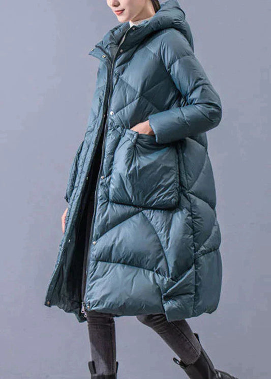 Woman wearing a long teal quilted hooded winter coat with front pockets, front view
