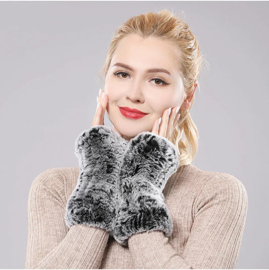 Woman wearing grey and black plush fingerless gloves with her hands near her face