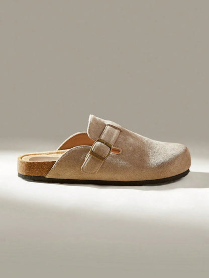 Side view of a taupe suede clog-style slide with a buckle strap and cork footbed