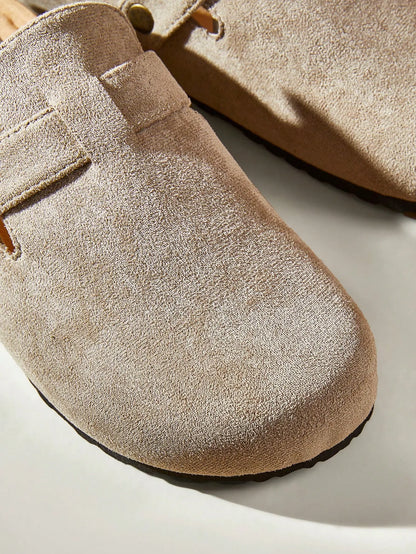 Close-up of the suede toe and buckle strap of a taupe clog-style slide