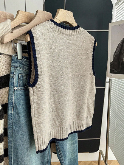 Grey knit sweater vest with navy contrast trim hanging on a hanger, front view