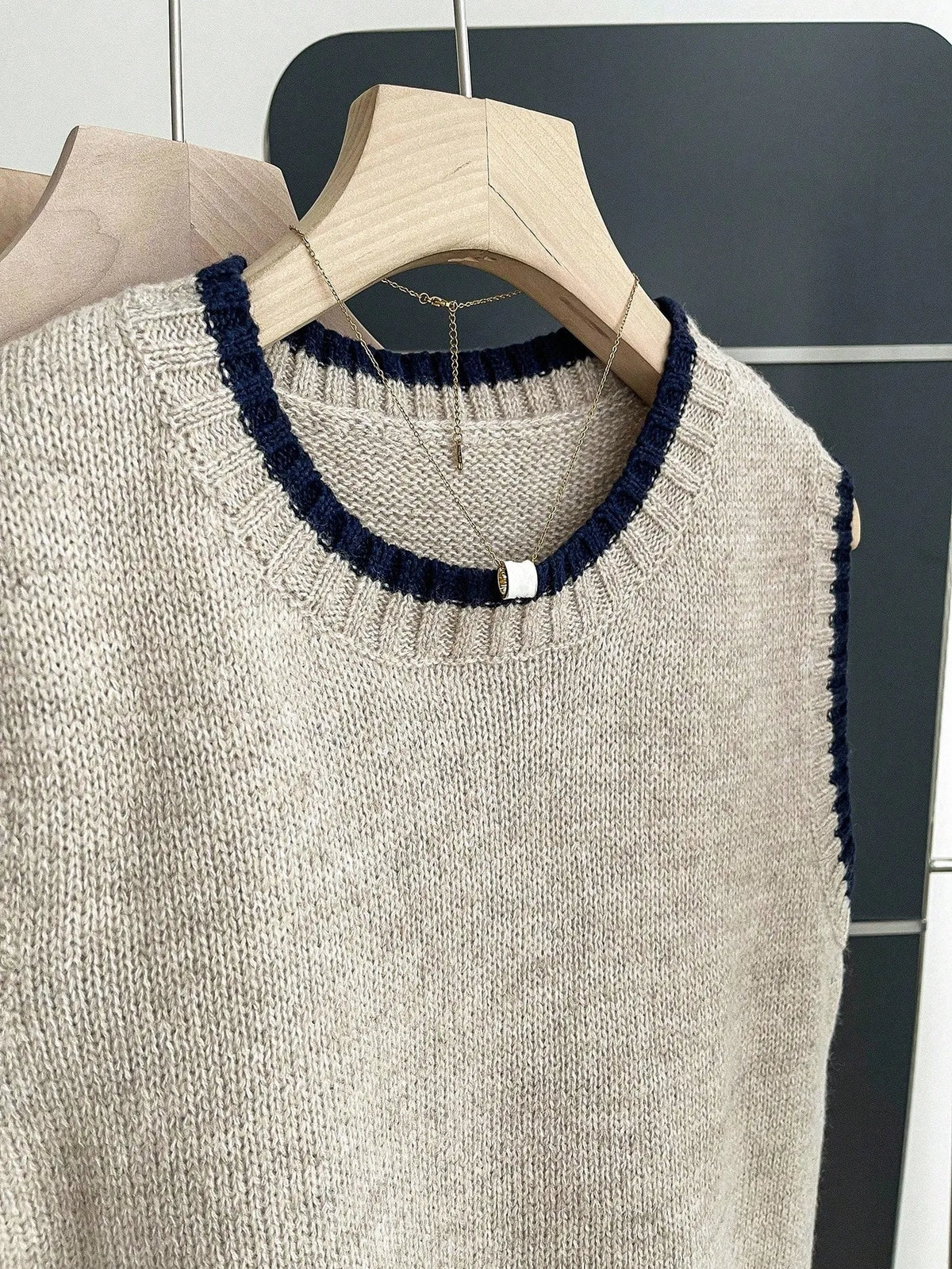 Close-up of the grey knit vest round neckline with navy contrast trim