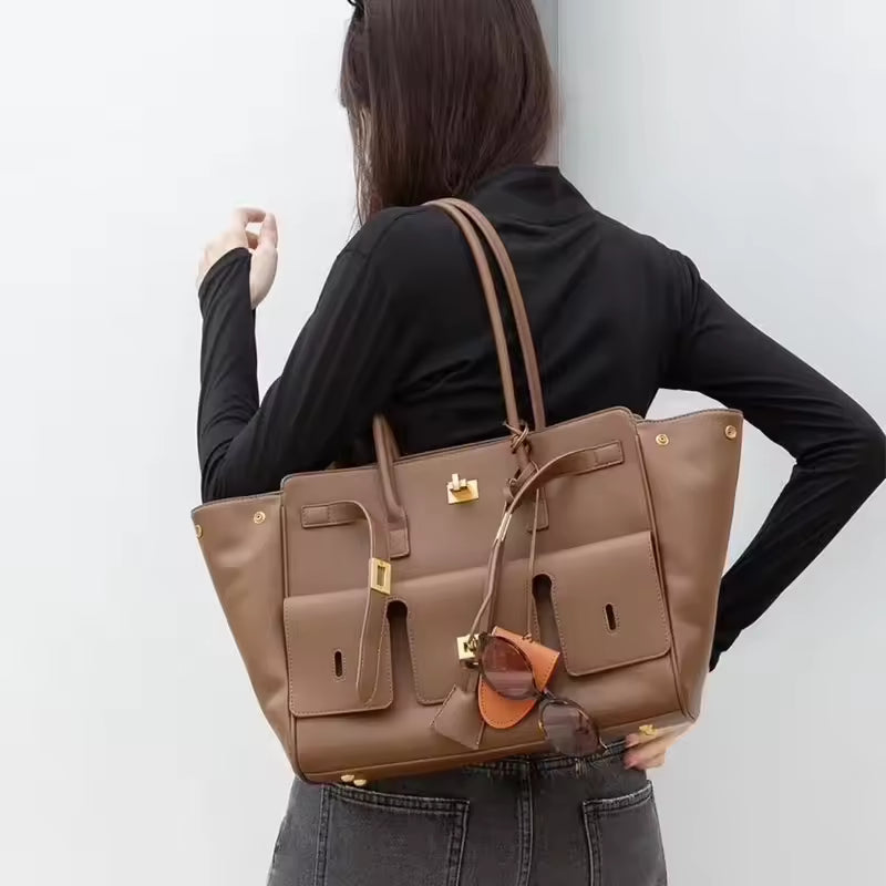 Woman in a black top carrying the brown tote bag on her shoulder, seen from the side