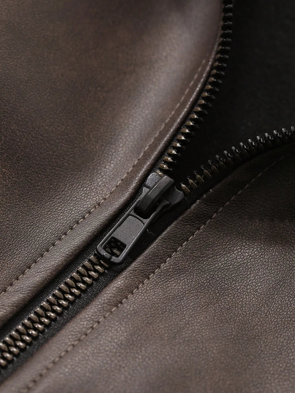 Close-up of the metal zipper and brown leather-look fabric of the jacket