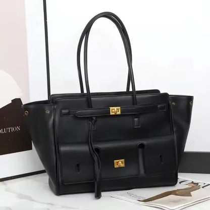 Black leather-look tote bag with two top handles, front pockets and gold clasps, shown on a white surface