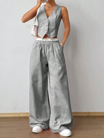 Woman in a grey pinstripe V-neck vest top and matching wide-leg pants with white sneakers, front view
