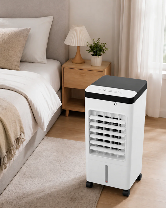 White portable air cooler fan with a black top panel next to a bed in a bedroom