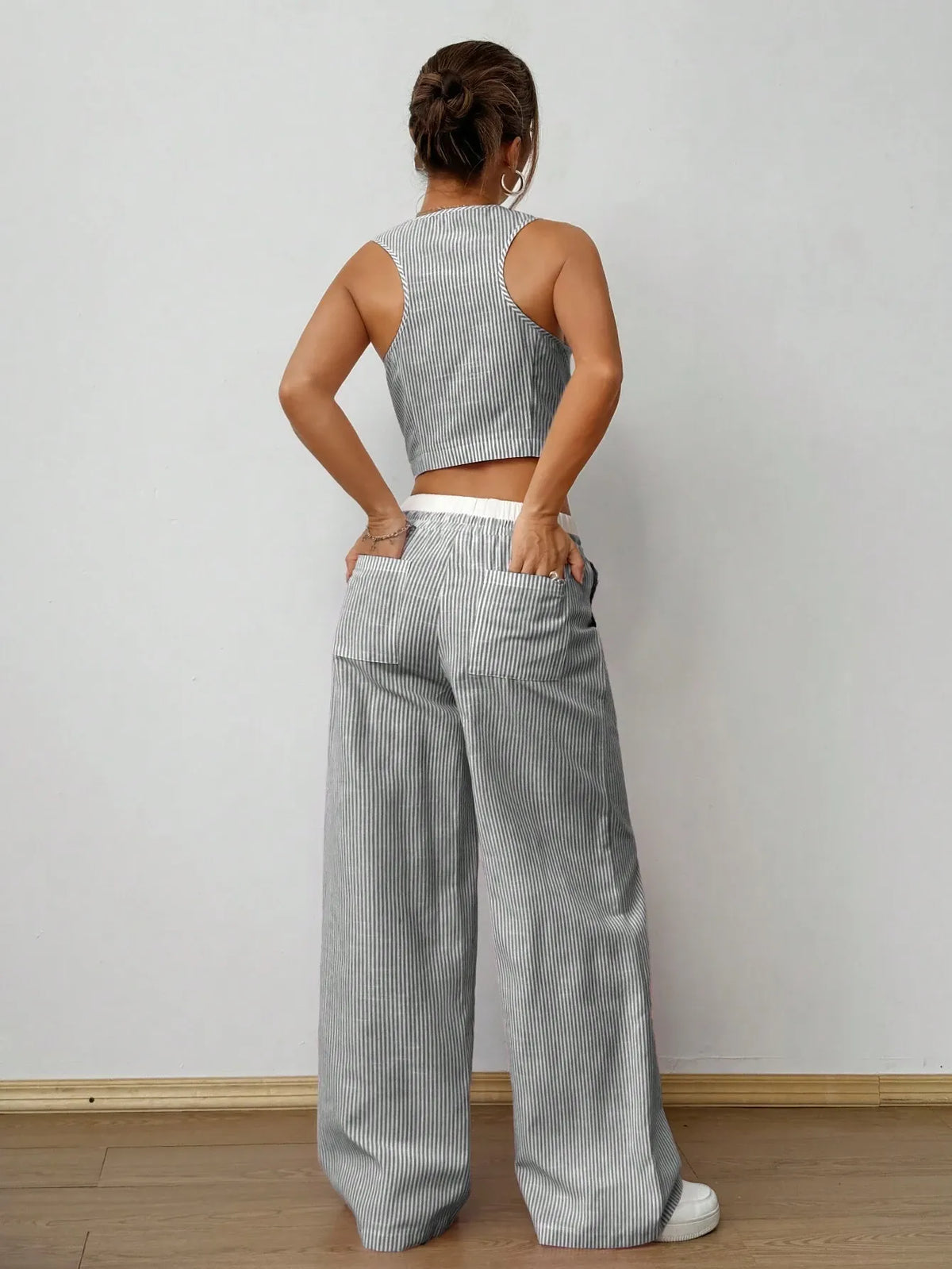 Back view of the grey pinstripe vest top and wide-leg pants, hands in the back pockets