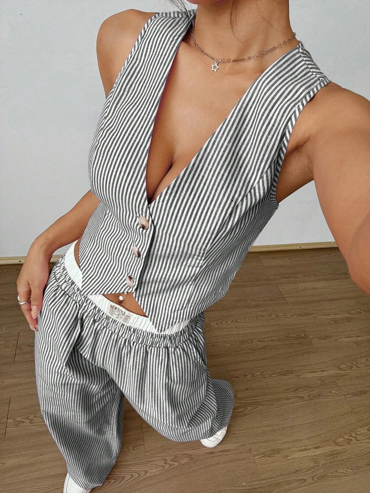 Grey pinstripe V-neck button-front vest top, close view in a leaning pose