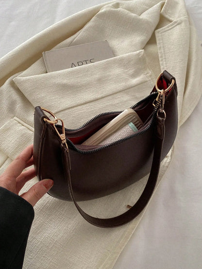 Dark brown half-moon bag with the top open to show the lining and a card inside