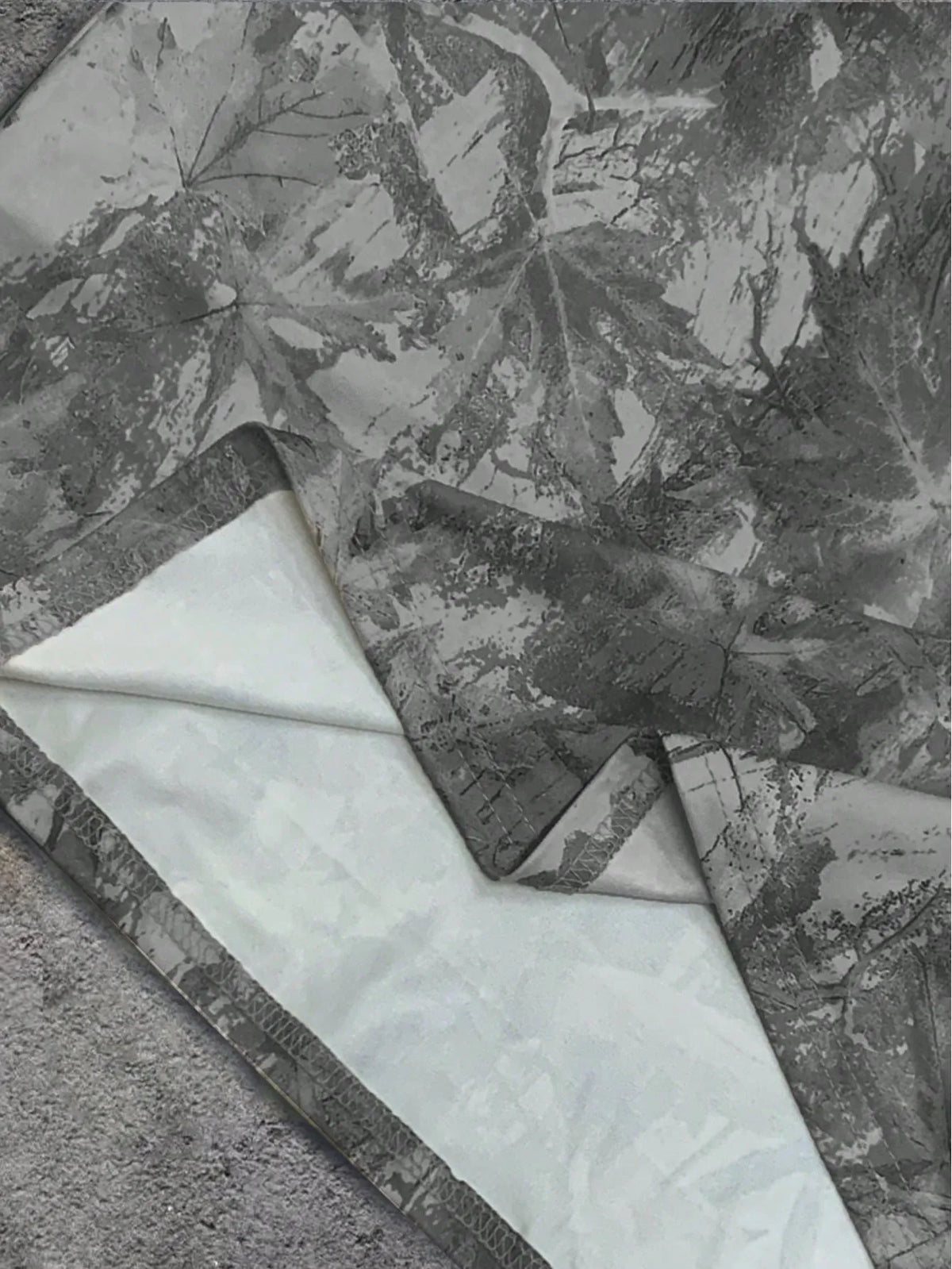 Close-up of the grey camo print fabric showing the white inner side and hem