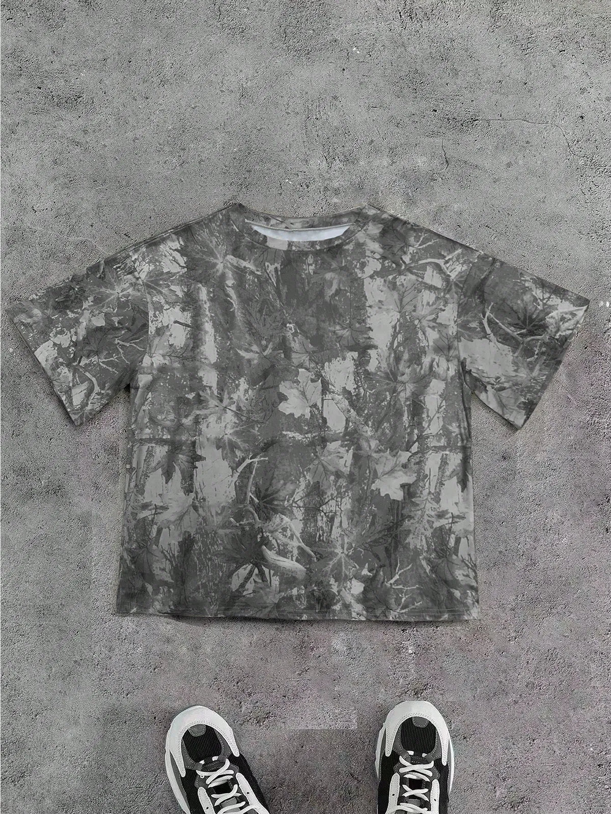 Grey camo print oversized T-shirt laid flat with black sneakers below