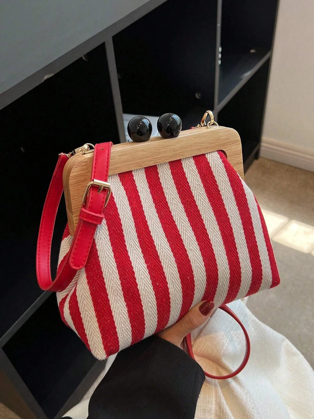 Red and cream striped bag with a wooden frame and two black ball clasps, front view