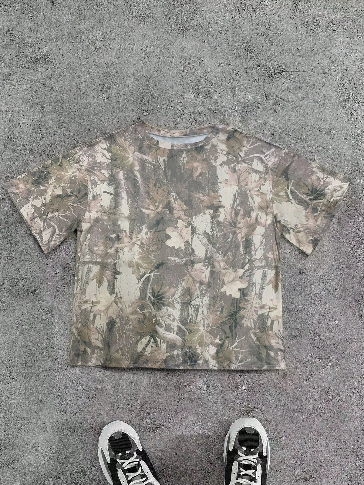 Olive beige camo print oversized T-shirt laid flat with black sneakers below