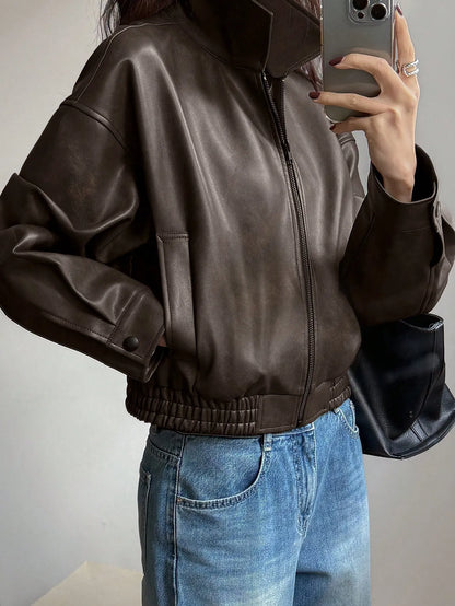Side view of the cropped dark brown leather-look jacket with an elastic hem, taking a mirror selfie