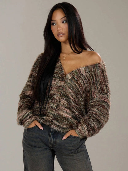 Woman wearing an oversized brown and grey striped knit cardigan off the shoulder with grey jeans