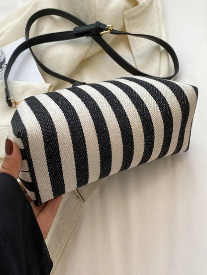 Black and cream striped bag held on its side to show the canvas body and black shoulder strap
