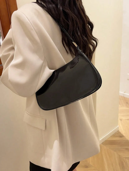 Woman carrying the glossy black half-moon bag on her shoulder, side view