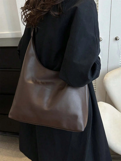 Woman carrying the dark brown slouchy shoulder bag on her shoulder, side view