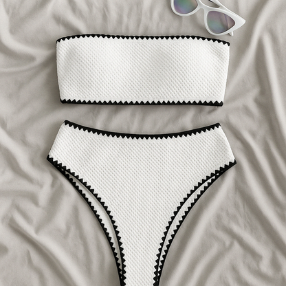 White textured bandeau bikini set with black zigzag trim, laid flat
