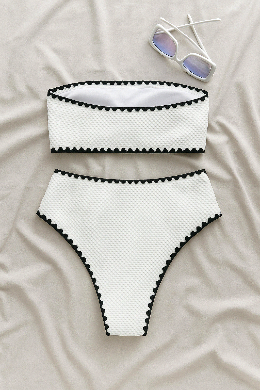 White textured bandeau top and high-waist bikini bottom with black trim, with sunglasses